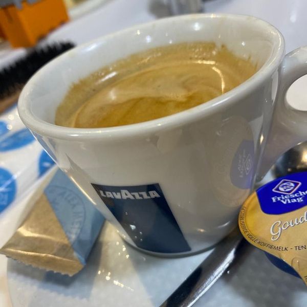 Kop koffie op de toonbank van de kapsalon, met kammen op de achtergrond